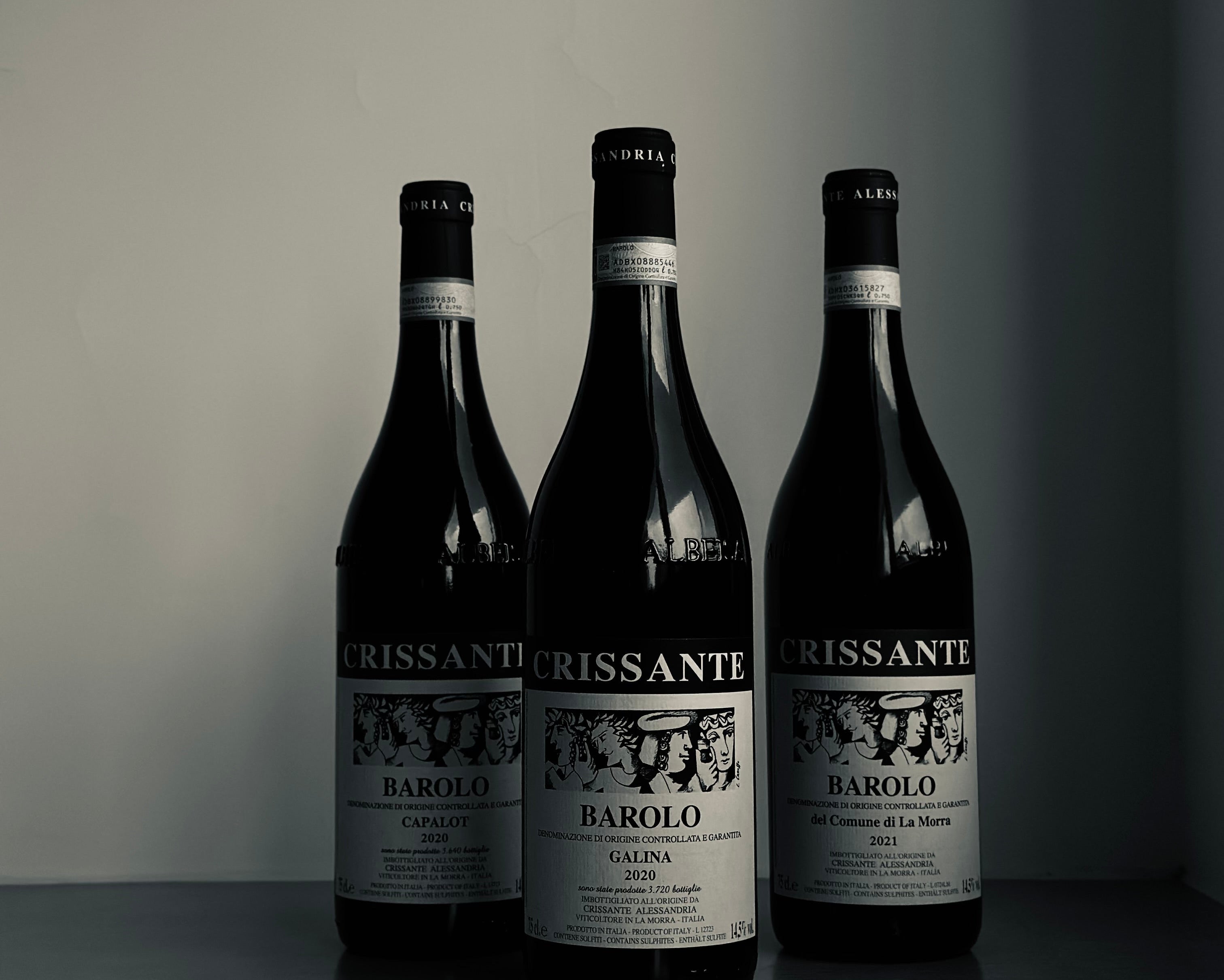 Three bottles of Crissante Barolo wine on a dark surface with a neutral background